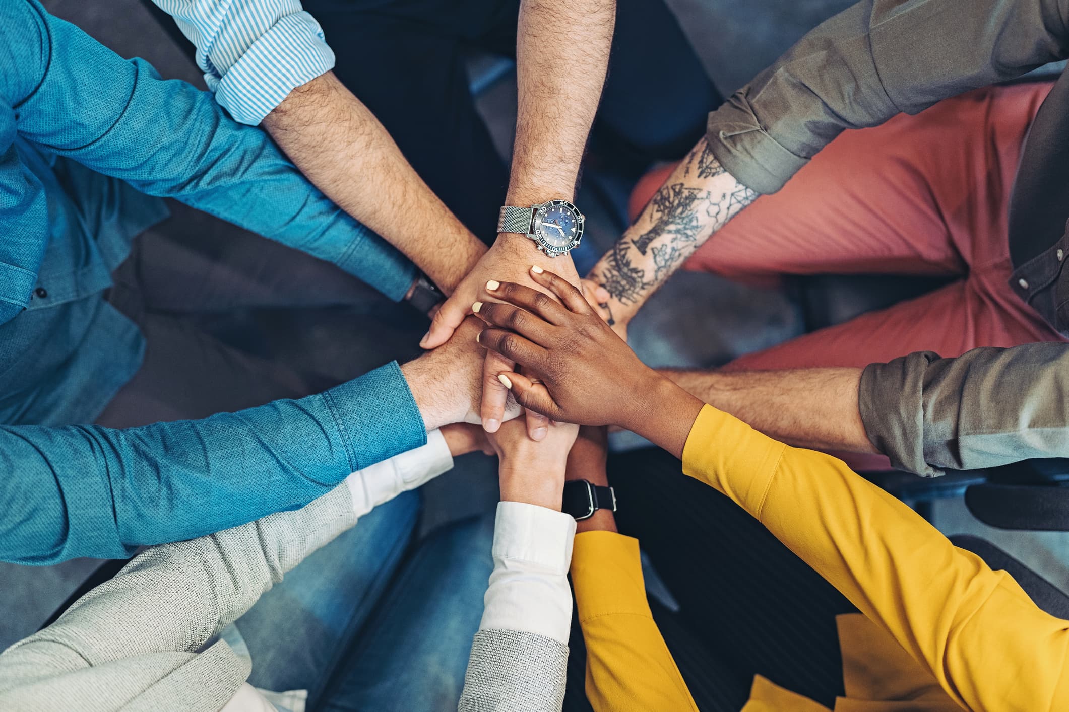 A group of people standing together with their hands in a circle