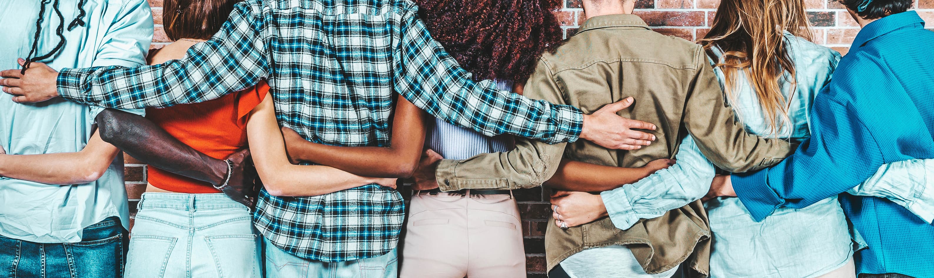 Diverse team members stadning together in a line with thier arms around each other